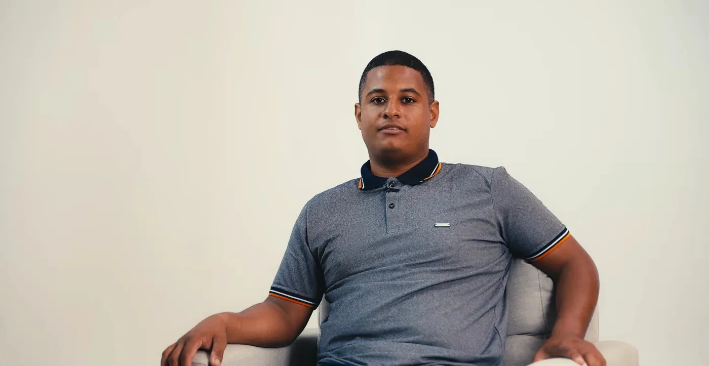 Raphael Martins, aluno do Portal Concursos, sentado em uma poltrona durante a gravação do depoimento