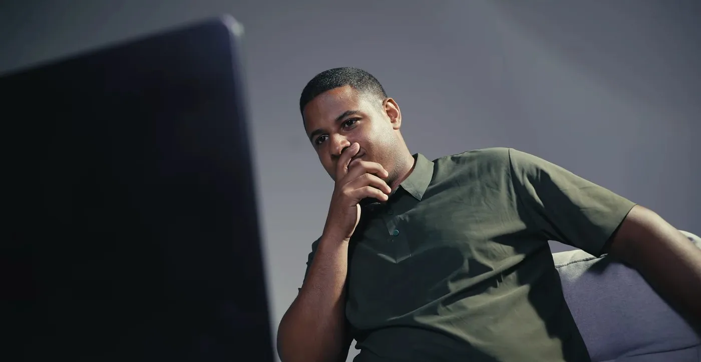 Raphael Martins pensativo, com a mão no queixo, diante de um notebook
